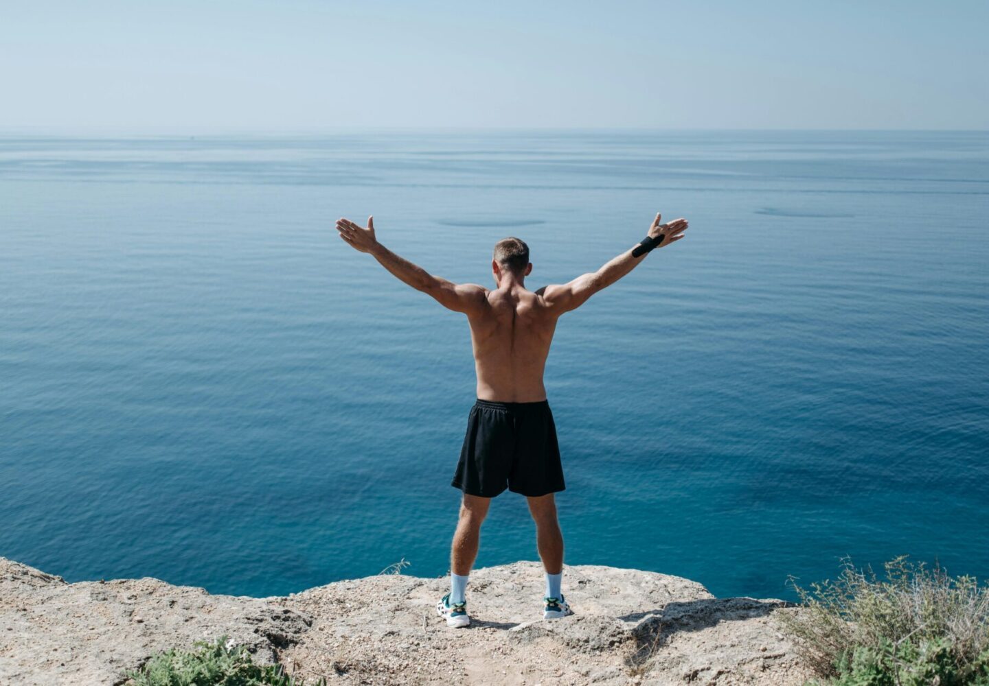 Man vitality standing on cliff by ocean