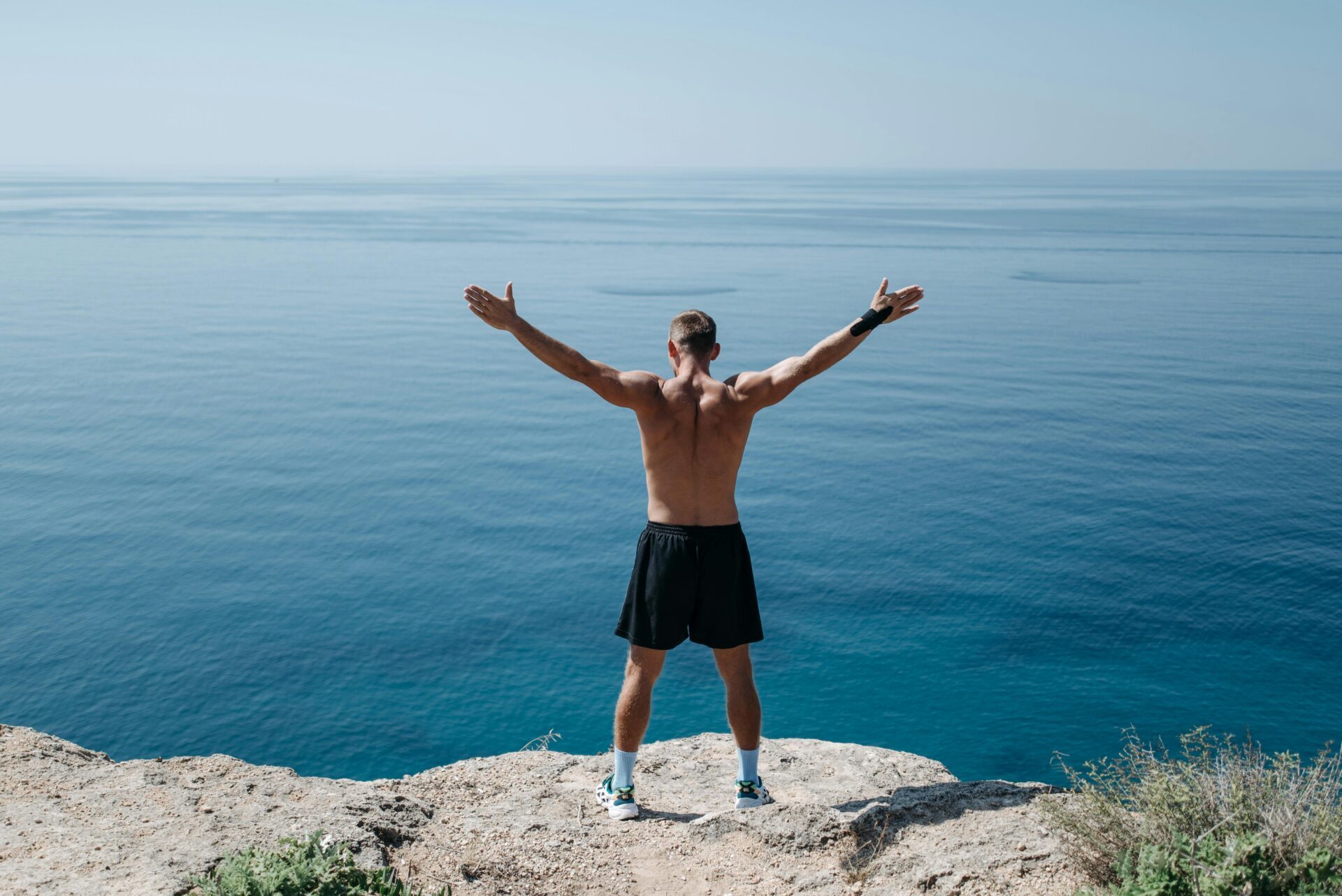 Man vitality standing on cliff by ocean